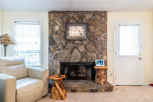 living room with a stone fireplace, plenty of natural light, and carpet