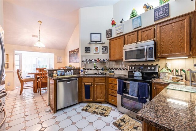 kitchen featuring sink, kitchen peninsula, decorative light fixtures, backsplash, and stainless steel appliances