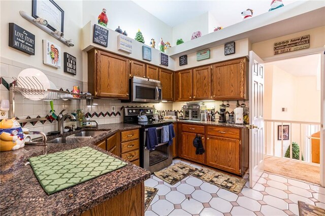 kitchen featuring appliances with stainless steel finishes, backsplash, light tile patterned floors, a high ceiling, and sink