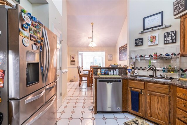 kitchen with high vaulted ceiling, backsplash, stainless steel appliances, decorative light fixtures, and sink