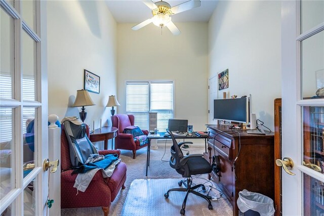 carpeted office space with a high ceiling and ceiling fan