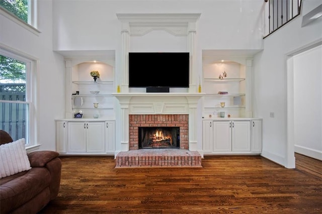 385 Guildhall Grv, Johns Creek, GA 30022 - living room featuring dark wood-style flooring, a high ceiling, built in shelves, and a brick fireplace
