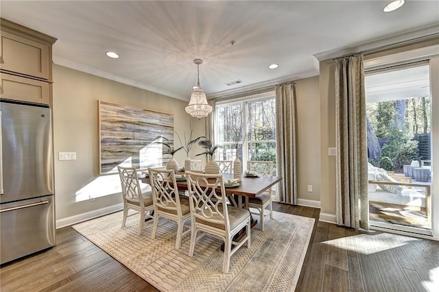 dining room with a chandelier, crown molding, and dark wood-type flooring