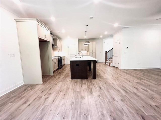 kitchen with black gas range oven, sink, a center island with sink, light hardwood / wood-style flooring, and hanging light fixtures