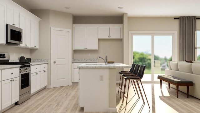 1924 Logan Ln SE, Conyers, GA 30094 - kitchen featuring appliances with stainless steel finishes, light wood-style flooring, an island with sink, white cabinetry, and light stone countertops