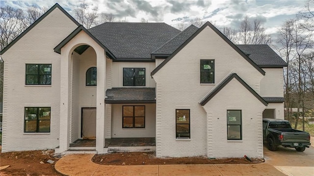 view of front of home with brick siding and a shingled roof