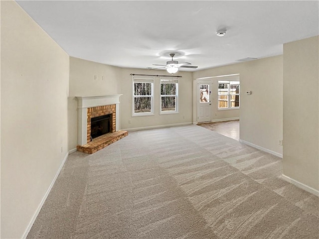 unfurnished living room with a brick fireplace, carpet, baseboards, and ceiling fan