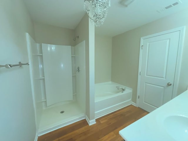 bathroom with hardwood / wood-style flooring, shower with separate bathtub, sink, and an inviting chandelier