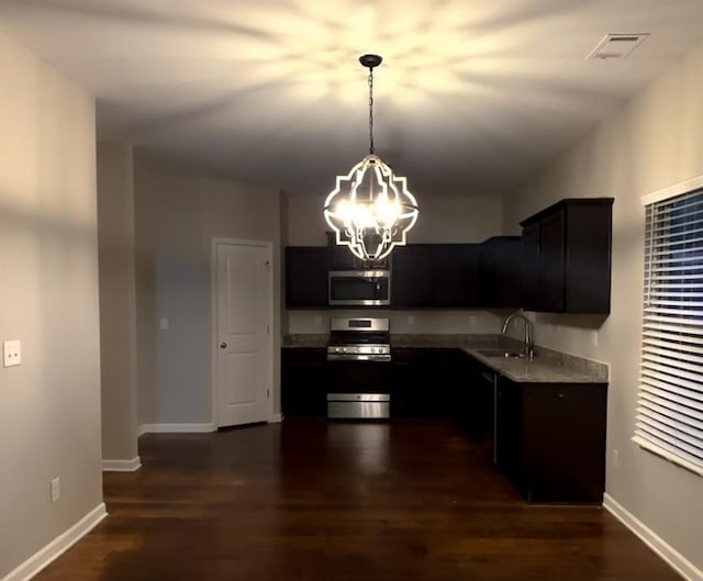 kitchen featuring dark wood-type flooring, sink, a chandelier, hanging light fixtures, and appliances with stainless steel finishes