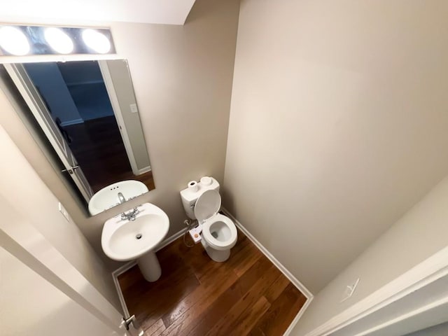 bathroom featuring toilet, sink, and hardwood / wood-style floors