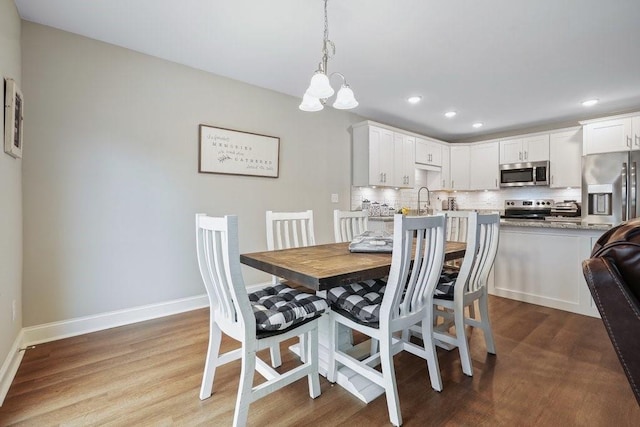 dining space featuring a notable chandelier, baseboards, wood finished floors, and recessed lighting