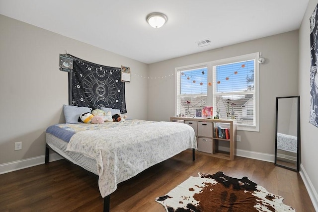 bedroom with visible vents, baseboards, and wood finished floors