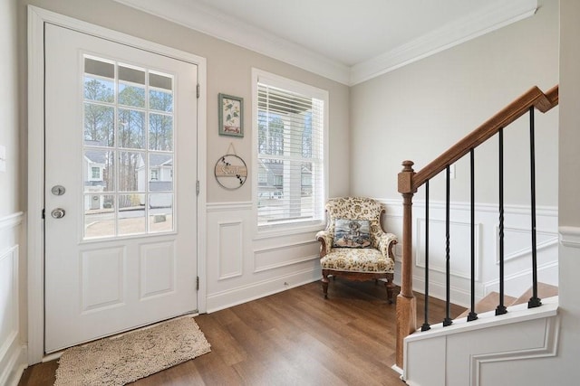 interior space featuring a wainscoted wall, stairs, ornamental molding, and wood finished floors