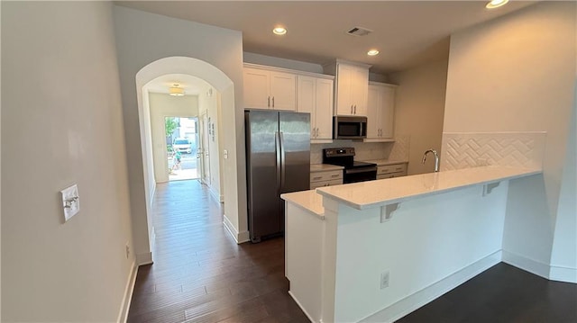 32 S Auburn Landing Pl, Auburn, GA 30011 - kitchen with stainless steel appliances, a peninsula, a breakfast bar, backsplash, and light countertops