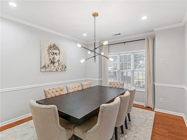 dining room with ornamental molding and light hardwood / wood-style flooring