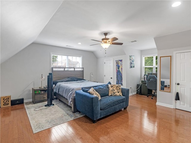 bedroom featuring lofted ceiling, hardwood / wood-style floors, multiple windows, and ceiling fan