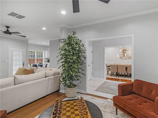 living room with ornamental molding, ceiling fan with notable chandelier, and light hardwood / wood-style flooring