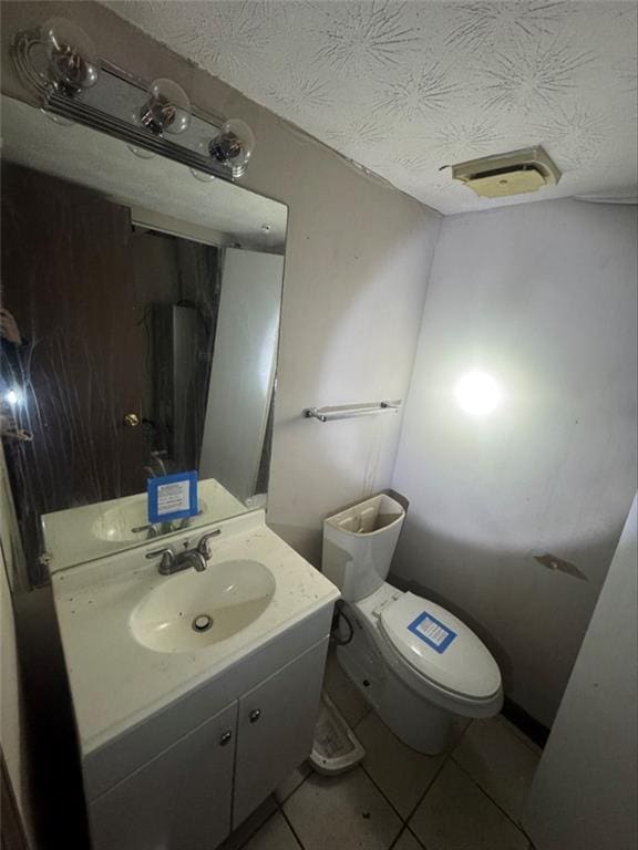 bathroom featuring tile patterned flooring, vanity, a textured ceiling, and toilet