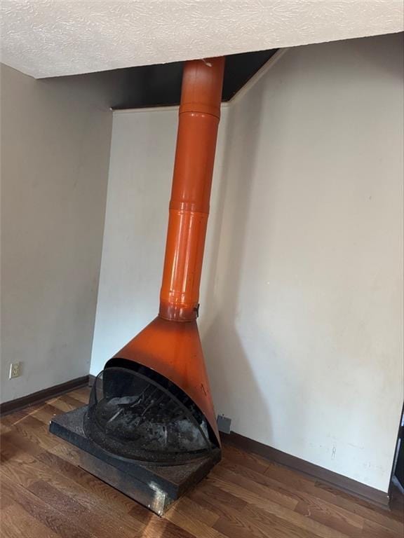 details featuring hardwood / wood-style flooring, a textured ceiling, and a wood stove