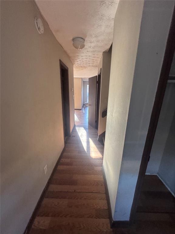 hall featuring dark wood-type flooring and a textured ceiling