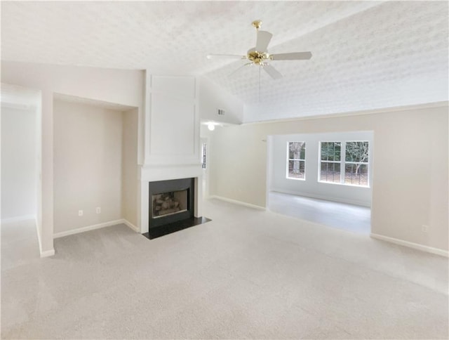 unfurnished living room with ceiling fan, a large fireplace, light carpet, and lofted ceiling