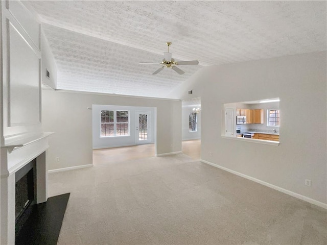 unfurnished living room with light carpet, vaulted ceiling, and ceiling fan