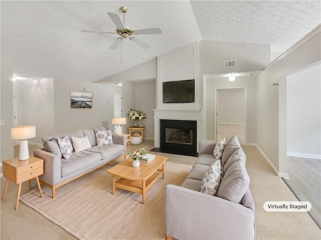 living room featuring a large fireplace, light carpet, vaulted ceiling, and ceiling fan