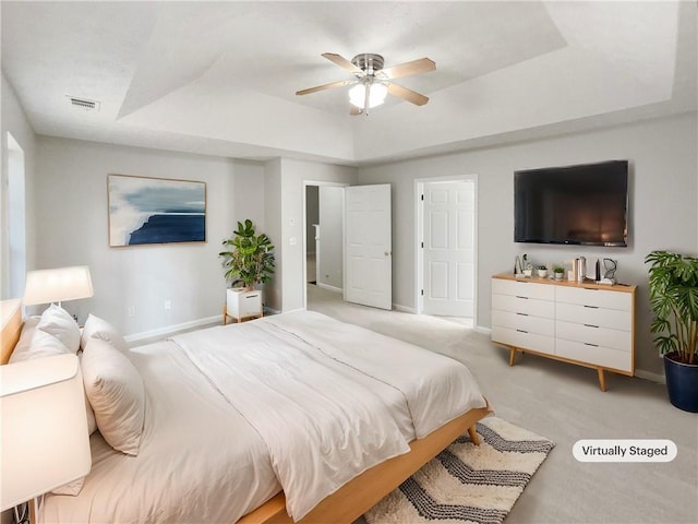 carpeted bedroom with ceiling fan and a tray ceiling