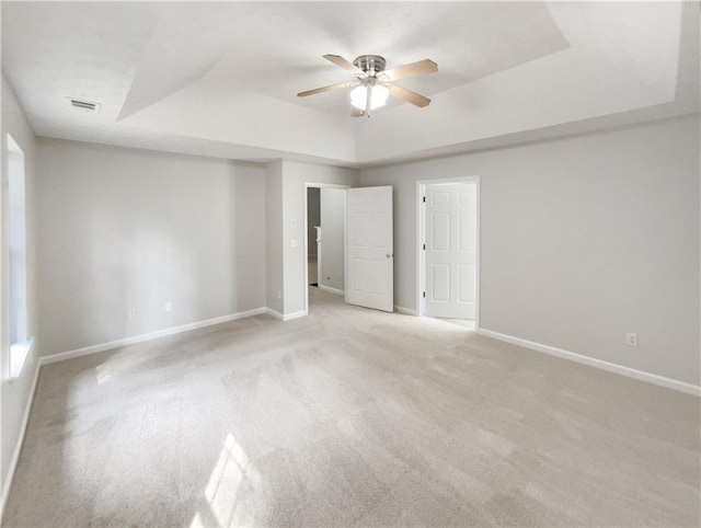 unfurnished bedroom with a tray ceiling, ceiling fan, and light colored carpet