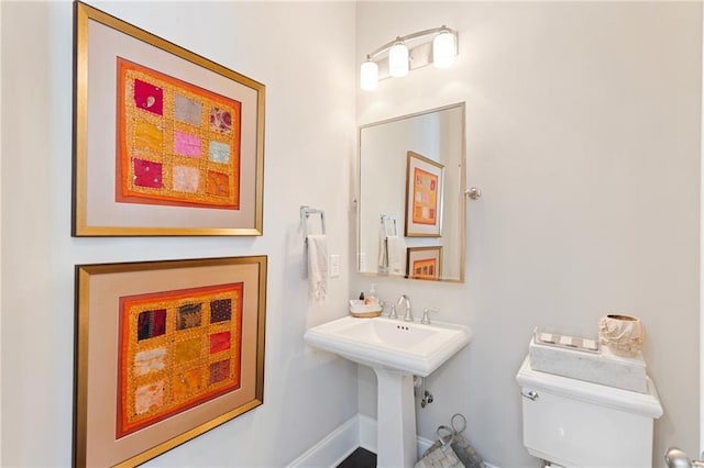 half bath featuring toilet and baseboards