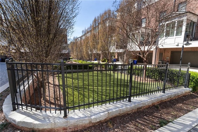 view of community with a lawn, an attached garage, and fence