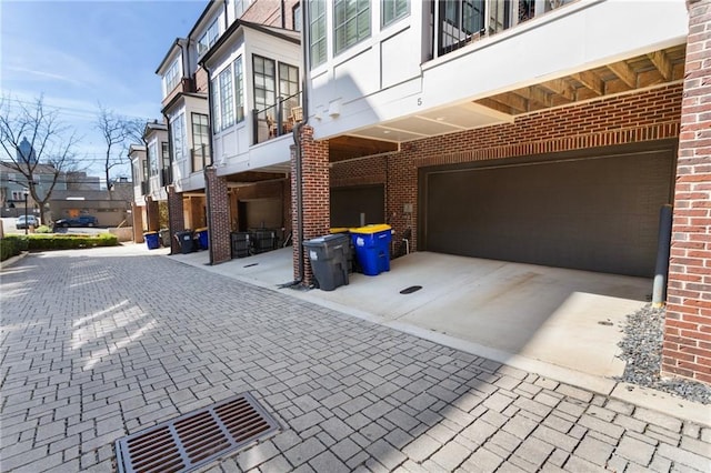 view of property exterior featuring concrete driveway, an attached garage, and brick siding