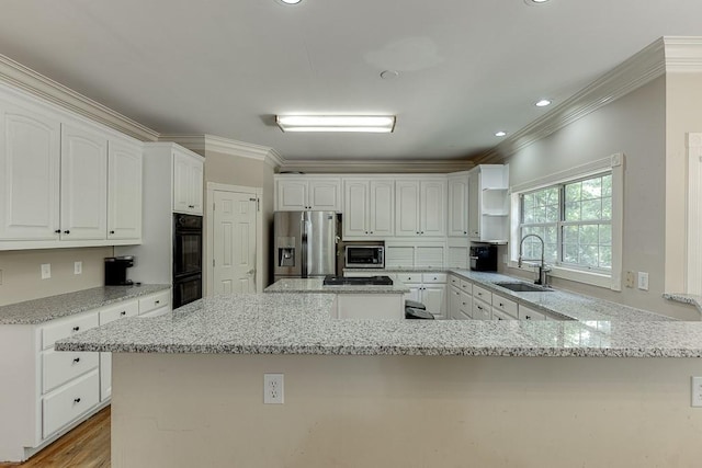 kitchen with light stone counters, a peninsula, a sink, ornamental molding, and appliances with stainless steel finishes