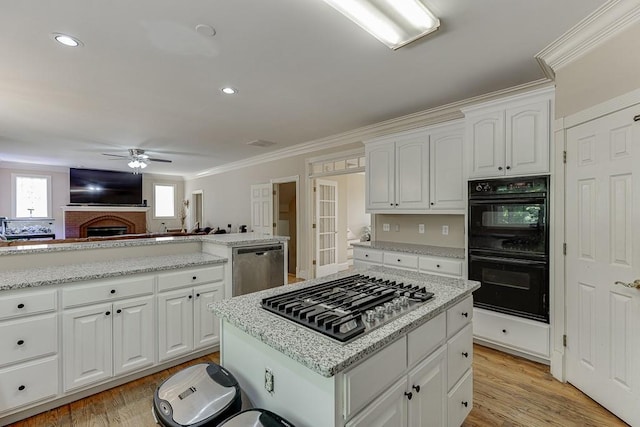 kitchen featuring stainless steel appliances, a ceiling fan, white cabinets, light wood-style floors, and ornamental molding