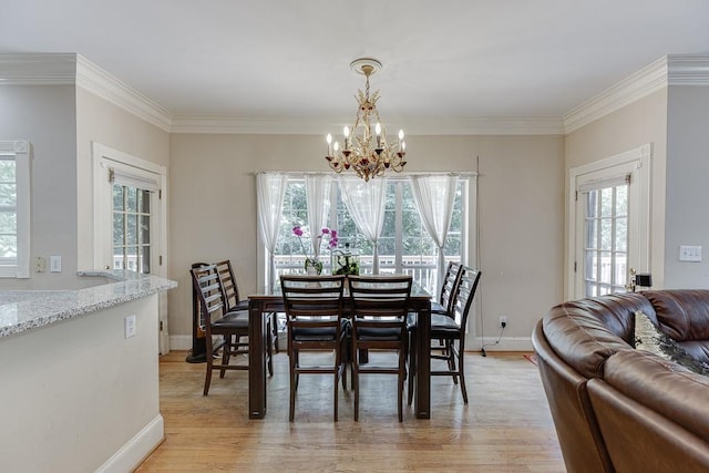 dining space with light wood-style floors, crown molding, and an inviting chandelier