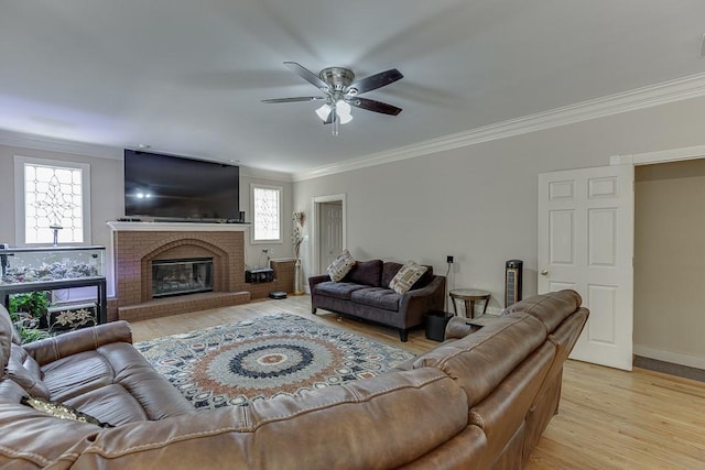 living room with baseboards, a ceiling fan, crown molding, light wood-style floors, and a fireplace