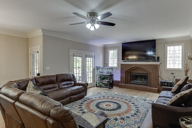 living room with french doors, a fireplace, ornamental molding, a ceiling fan, and wood finished floors