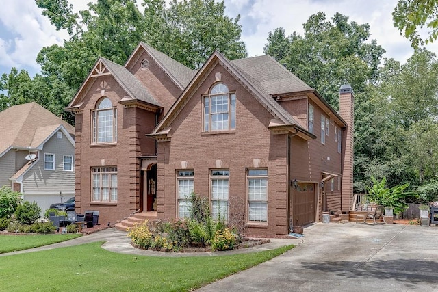 view of front of house featuring driveway, brick siding, and a chimney