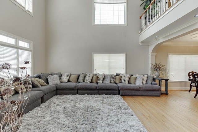 living area featuring plenty of natural light, arched walkways, crown molding, and wood finished floors