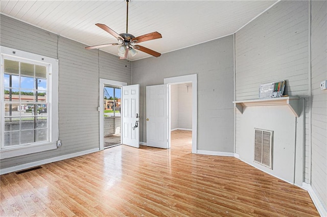 unfurnished living room with a high ceiling, wood walls, wood-type flooring, and ceiling fan