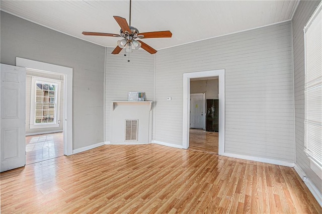 unfurnished living room featuring ceiling fan, a towering ceiling, hardwood / wood-style floors, and a fireplace