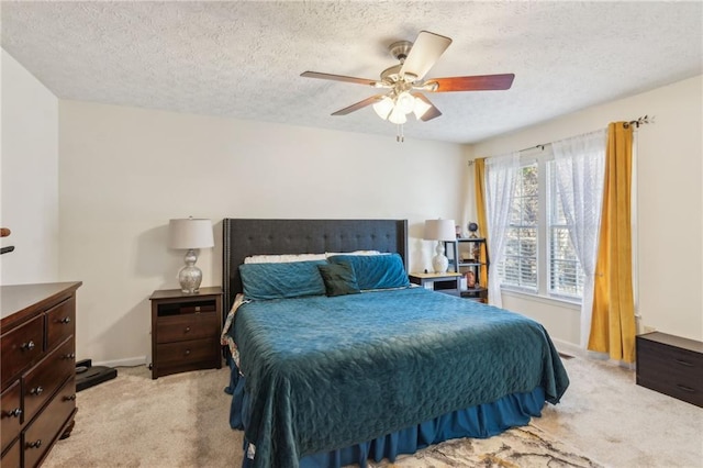 bedroom featuring light carpet, ceiling fan, a textured ceiling, and baseboards