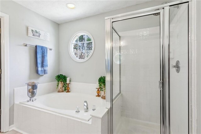 full bath featuring a textured ceiling, a stall shower, and a bath