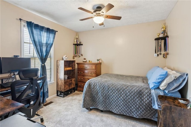 bedroom with light carpet, baseboards, a ceiling fan, and a textured ceiling