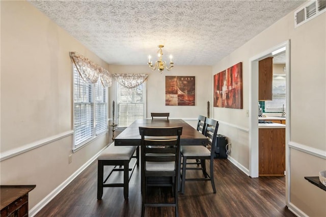 dining room featuring dark wood-style flooring, visible vents, a notable chandelier, and baseboards