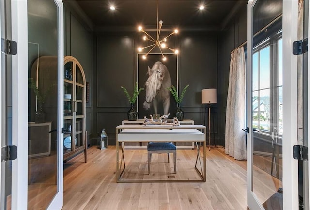 home office with french doors, a decorative wall, and wood finished floors