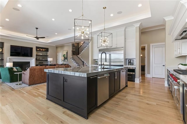 kitchen featuring white cabinets, a fireplace, appliances with stainless steel finishes, and a raised ceiling