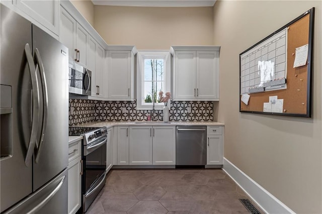 kitchen featuring baseboards, stainless steel appliances, light countertops, and decorative backsplash