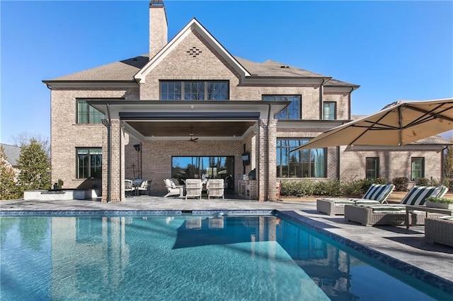 back of property with a chimney, a patio area, brick siding, and an outdoor living space