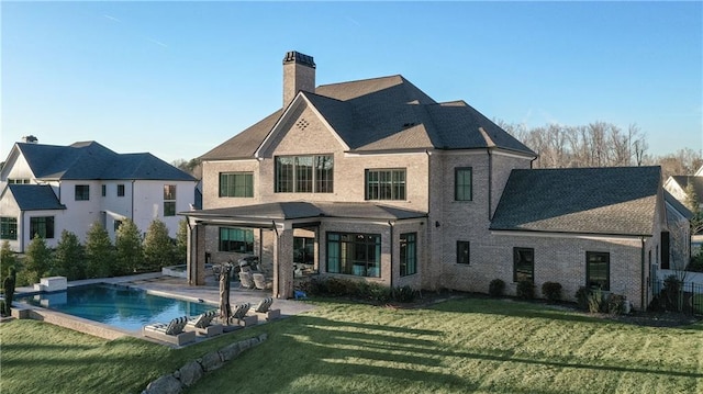 back of property featuring a fenced in pool, a patio, a chimney, a yard, and brick siding